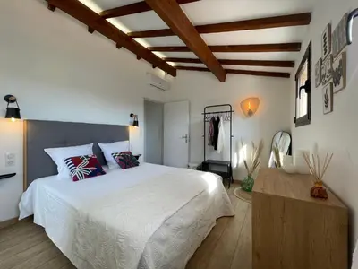 a bedroom with a large white bed and wooden ceilings at Les Hauts de Capo - Domaine privé à proximité de Porto-Vecchio in Lecci