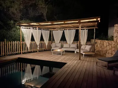 a wooden deck with a couch and a pergola at Les Hauts de Capo - Domaine privé à proximité de Porto-Vecchio in Lecci