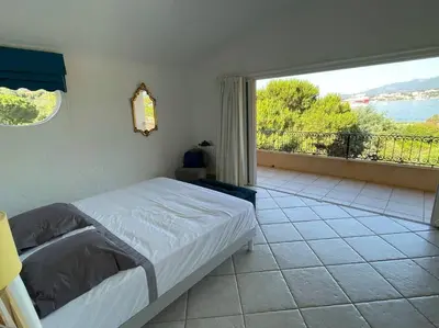 a bedroom with a bed and a large window at Villa Bianca - Vue imprenable Mer & Porto-Vecchio, Piscine chauffée à débordement, Accès privé plage in Porto-Vecchio