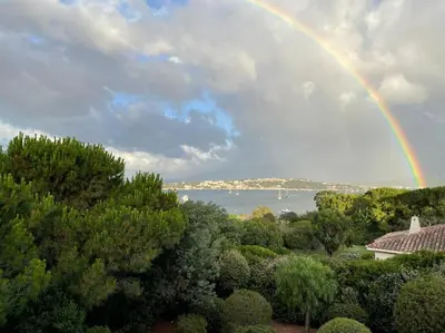 a rainbow in the sky over the water with trees at Villa Bianca - Vue imprenable Mer & Porto-Vecchio, Piscine chauffée à débordement, Accès privé plage in Porto-Vecchio