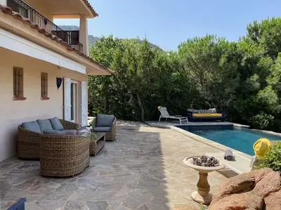a patio with wicker furniture next to a swimming pool at Villa Bianca - Vue imprenable Mer & Porto-Vecchio, Piscine chauffée à débordement, Accès privé plage in Porto-Vecchio