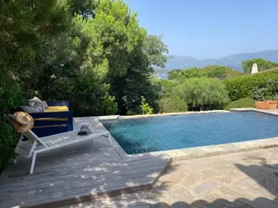 a swimming pool with a deck and a chair next to it at Villa Bianca - Vue imprenable Mer & Porto-Vecchio, Piscine chauffée à débordement, Accès privé plage in Porto-Vecchio