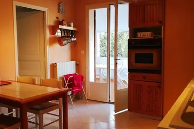 a kitchen with a table and a door to a balcony at Mare è Monte , jardin méditerranéen et exotique. in Ghisonaccia