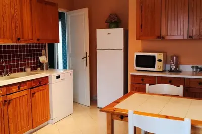 a kitchen with a white refrigerator and a table at Mare è Monte , jardin méditerranéen et exotique. in Ghisonaccia