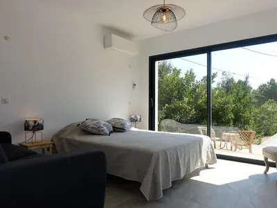 a white bedroom with a bed and a large window at Apartment Villa Kalliste by Interhome in Favone