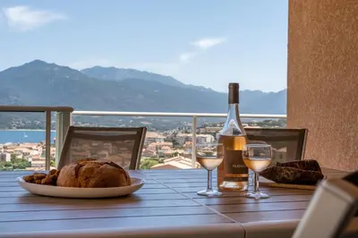 a table with a bottle of wine and a plate of bread and wine glasses at Casa a cucina in Propriano
