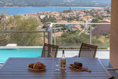 a table with bread and a bottle of wine and a view at Casa a cucina in Propriano