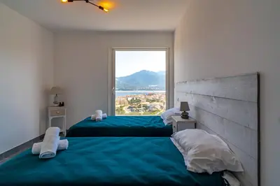 two beds in a room with a large window at Casa a cucina in Propriano