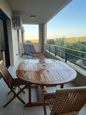 a wooden table and chairs on a balcony at Appartement climatisé Pinarello in Zonza
