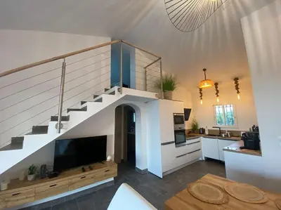 a living room with a staircase and a kitchen at villa CASA TOTTI vue mer avec piscine in Porto-Vecchio
