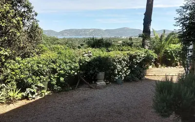 a garden with trees and bushes with mountains in the background at Villa ANCHORAGE vue mer panoramique Roof top Piscine a debordement in Porto-Vecchio