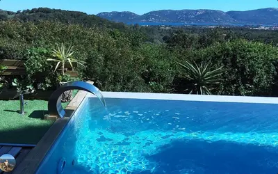 a blue swimming pool with a water fountain at Villa ANCHORAGE vue mer panoramique Roof top Piscine a debordement in Porto-Vecchio