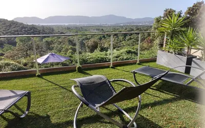 a chair and an umbrella on a balcony with a view at Villa ANCHORAGE vue mer panoramique Roof top Piscine a debordement in Porto-Vecchio