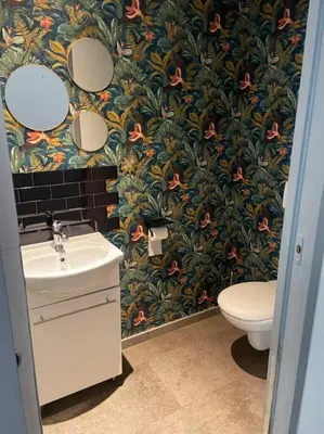 a bathroom with a sink and a toilet with a floral wallpaper at Villa 3 chambres avec piscine privative in Ajaccio