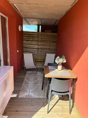 a room with a table and chairs on a deck at Résidence les Hameaux de Saint Cyprien appartement LUNA 132 in Lecci