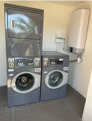 a laundry room with two washing machines and a tv at Résidence les Hameaux de Saint Cyprien appartement LUNA 132 in Lecci