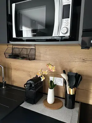 a microwave above a kitchen counter with a vase of flowers at Résidence les Hameaux de Saint Cyprien appartement LUNA 132 in Lecci