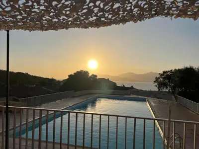 a pool with the sunset in the background at Bella Vista 34 , T2 vue mer, piscine ,climatisé Porticcio in Porticcio