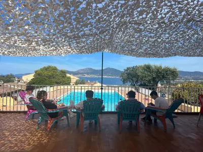 a group of people sitting around a table by a pool at Bella Vista 34 , T2 vue mer, piscine ,climatisé Porticcio in Porticcio