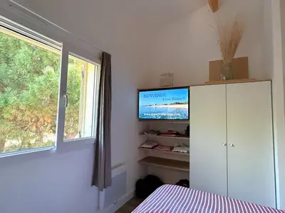 a bedroom with a tv and a cabinet and a window at Appart Cala Rossa - Porto-Vecchio - Mer à pied in Lecci