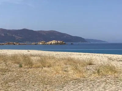 a large body of water with mountains in the background at Golfe de Sagone Plage du Liamone Maison pieds dans l'eau in Casaglione