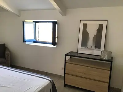 a bedroom with a bed and a window and a dresser at Golfe de Sagone Plage du Liamone Maison pieds dans l'eau in Casaglione