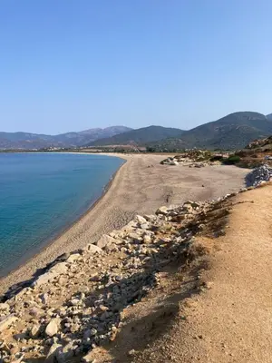 a beach with rocks and water and mountains in the background at Golfe de Sagone Plage du Liamone Maison pieds dans l'eau in Casaglione