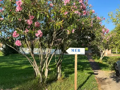 a sign in front of a tree with pink flowers at Résidence Marina di pinarello Mini Villa 6 personnes à 400 m de la plage in Zonza