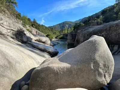 a river with large rocks in the water at Résidence Marina di pinarello Mini Villa 6 personnes à 400 m de la plage in Zonza