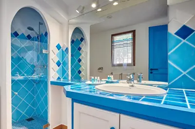 a blue bathroom with a sink and a shower at Résidence Belvedere de Palombaggia in Porto-Vecchio