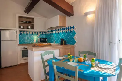 a kitchen with a blue table and chairs in a kitchen at Résidence Belvedere de Palombaggia in Porto-Vecchio