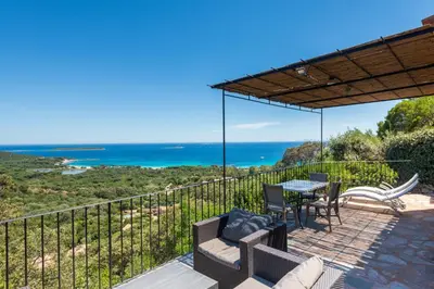 a patio with a table and chairs and the ocean at Résidence Belvedere de Palombaggia in Porto-Vecchio