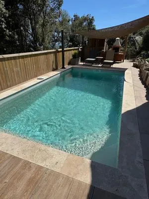 a swimming pool with blue water in a backyard at Bel appartement dans Villa avec piscine en Corse du Sud in Grossa