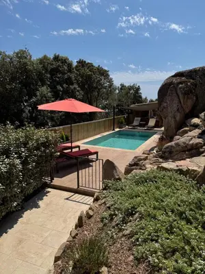 a swimming pool with a red umbrella and a table and sidx sidx sidx at Bel appartement dans Villa avec piscine en Corse du Sud in Grossa