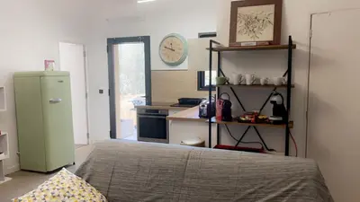 a bedroom with a bed and a kitchen with a refrigerator at Bel appartement dans Villa avec piscine en Corse du Sud in Grossa