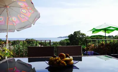 a bowl of fruit on a table with an umbrella at Villa à Pinarello-2mn à pied de la plage-vue mer in Pinarellu