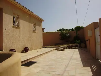 an empty courtyard with a building and a wall at Villa à Pinarello-2mn à pied de la plage-vue mer in Pinarellu