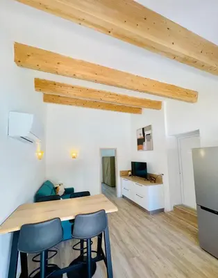 a kitchen and living room with a wooden table and chairs at Maison d’hôtes Joséphine in Ajaccio