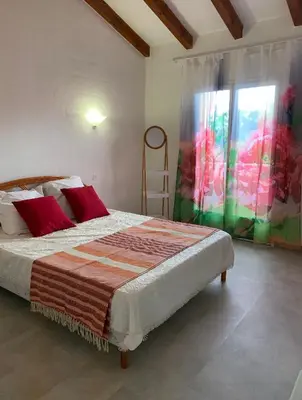 a bedroom with a bed with red pillows and a window at Villa de charme à Marina di fiori in Porto-Vecchio