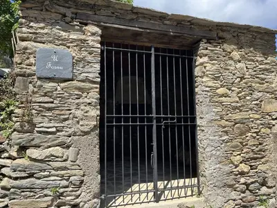 a gate on the side of a stone building at Le Refuge de la Tour entre mer et ciel in Porri