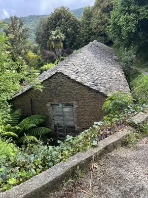 an old brick house with a roof on a hill at Le Refuge de la Tour entre mer et ciel in Porri