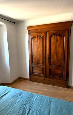 a wooden cabinet in the corner of a bedroom at A Torra entre mer et ciel in Porri