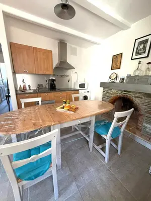 a kitchen with a wooden table with chairs and a fireplace at A Torra entre mer et ciel in Porri