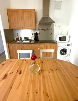 a kitchen with a wooden table with a vase with a rose in it at A Torra entre mer et ciel in Porri