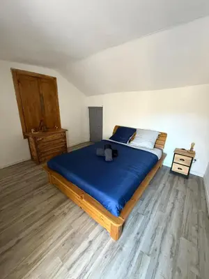 a bedroom with a bed with blue sheets and a wooden floor at A Torra entre mer et ciel in Porri