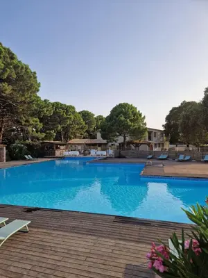 a large blue swimming pool with chairs and trees at Résidence Fiori di Cala Rossa in Lecci
