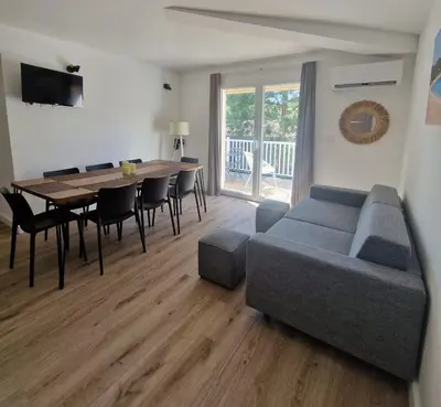 a living room with a couch and a table and chairs at Résidence Fiori di Cala Rossa in Lecci