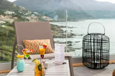 a table with drinks and a bird cage on a balcony at Village de vacances Paese di Lava, Grand Ajaccio in Alata