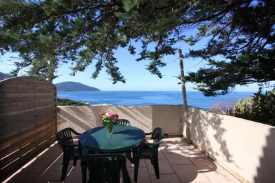 a table and chairs on a patio with a view of the ocean at Village de vacances Paese di Lava, Grand Ajaccio in Alata