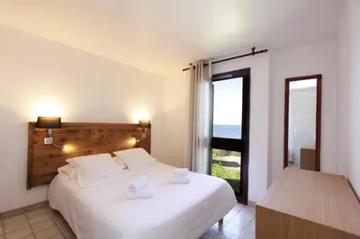 a bedroom with a bed with a view of the ocean at Village de vacances Paese di Lava, Grand Ajaccio in Alata